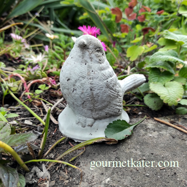 Kleiner Vogel aus Beton im Garten